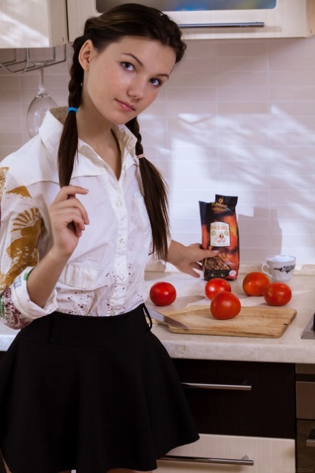 Pretty teen Iva strips down naked in the kitchen and displays her furry crotch